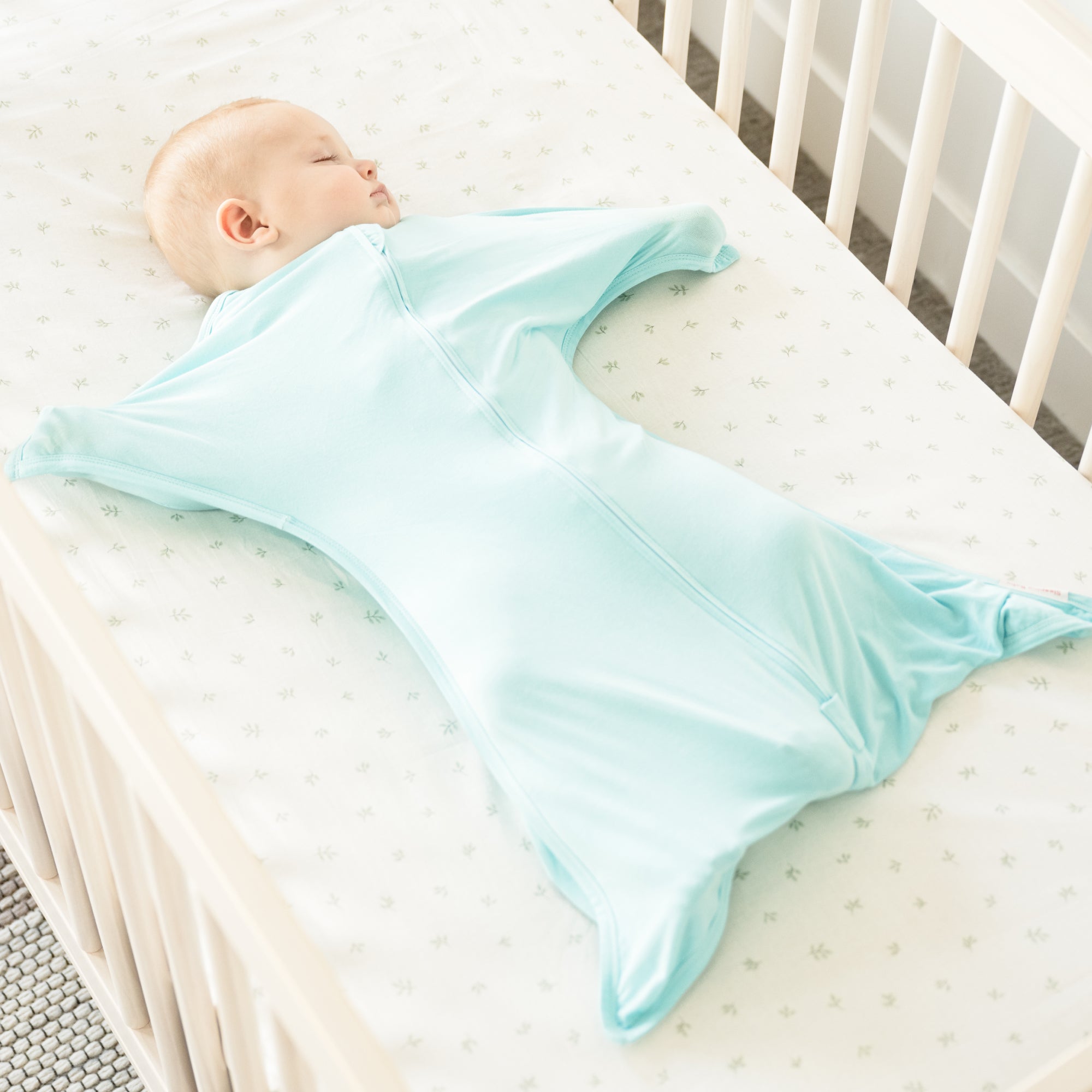 Baby sleeping in Sea Glass bamboo swaddle transition