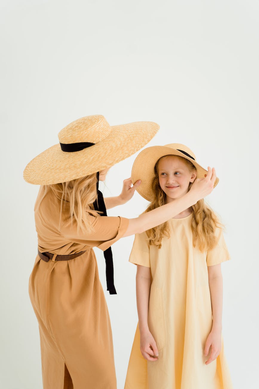 woman wearing a sunhat fixing a girl s hat